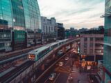 Dynamic cityscape featuring an elevated train amidst modern architecture and busy streets.