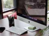 A clean, organized desk setup featuring a computer display, keyboard, and office supplies.