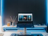 Contemporary desk setup featuring a laptop, electronic accessories, and neon lighting for a stylish workspace.
